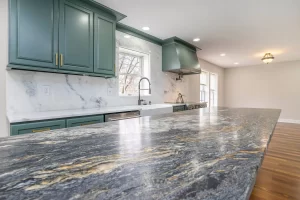 Modern kitchen with green cabinets, granite countertops, marble backsplash, and stainless steel appliances