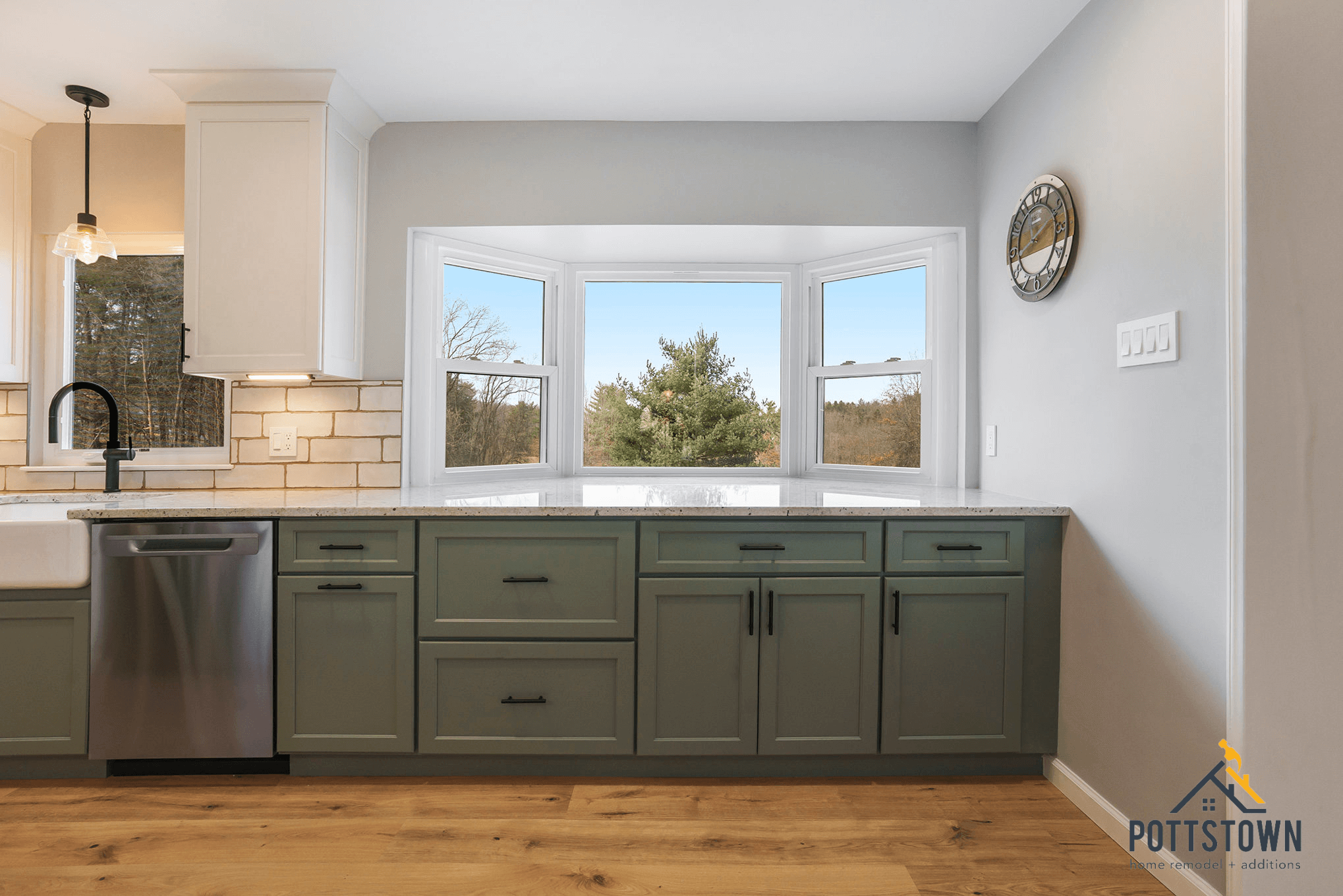 Modern kitchen remodel with green shaker cabinets, quartz countertop, and large bay window overlooking trees