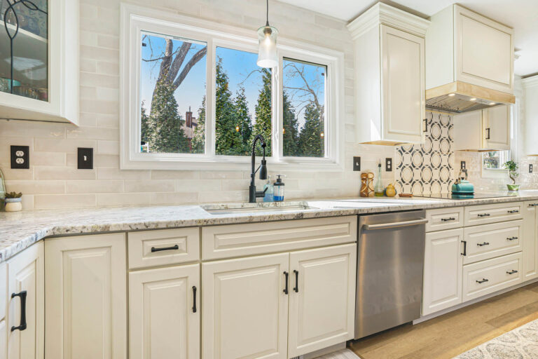 Modern cream shaker kitchen cabinets with granite countertops, subway tile backsplash, and stainless steel appliances