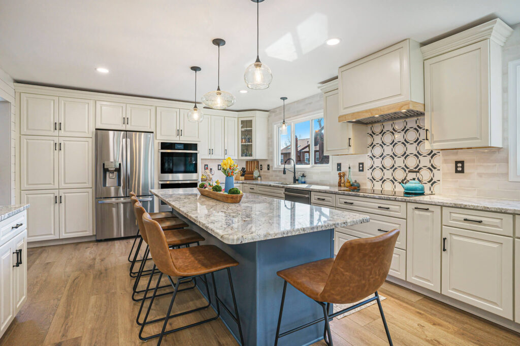 Modern kitchen remodel with cream shaker cabinets, granite island, stainless steel appliances, and pendant lighting