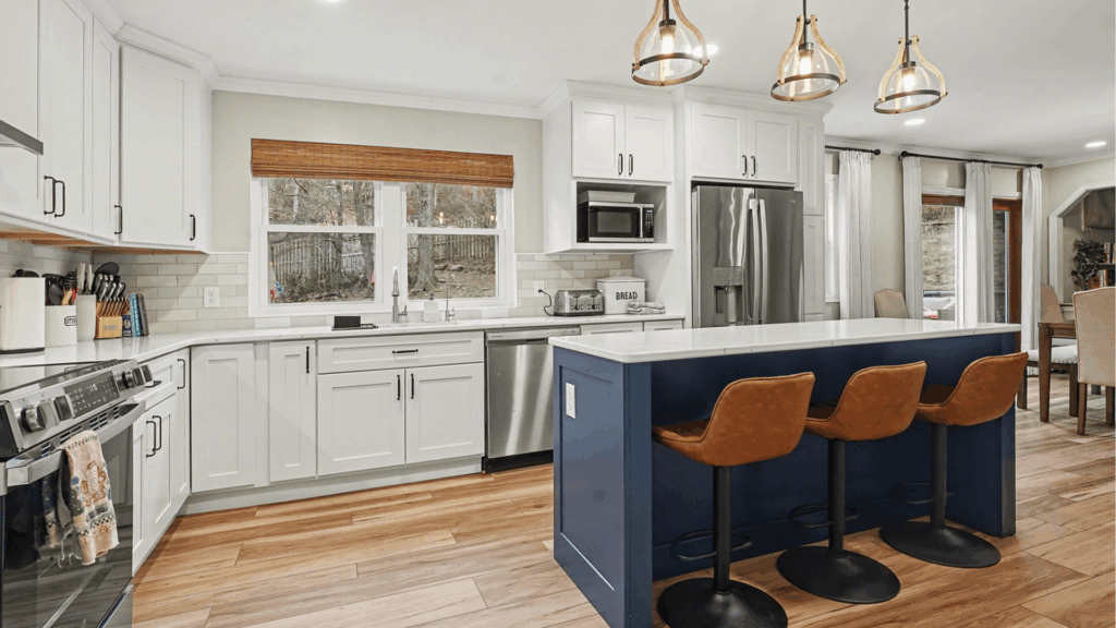 Modern kitchen remodel with white shaker cabinets, navy island, stainless steel appliances, and wood flooring