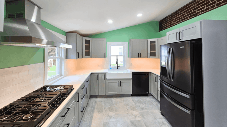 Modern kitchen remodel with gray shaker cabinets, green accent walls, black appliances, and tile flooring by Pottstown Construction Company