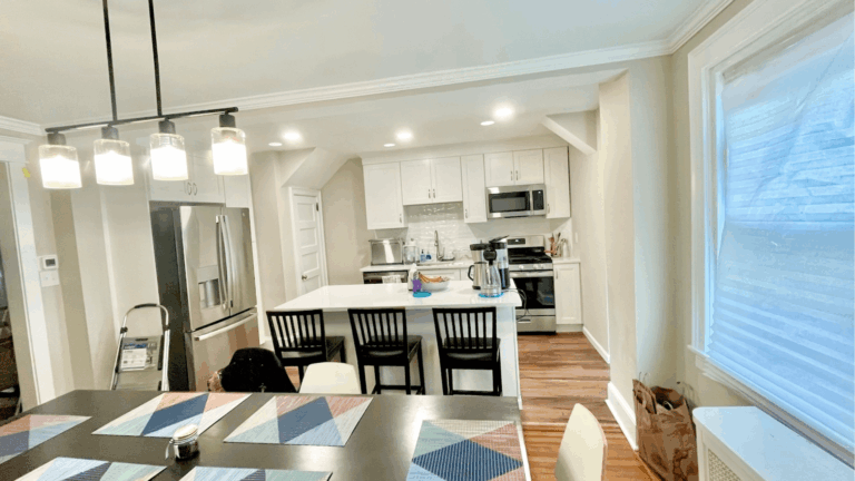 Modern kitchen remodel with white cabinetry, stainless steel appliances, island seating, and pendant lighting by Pottstown Construction
