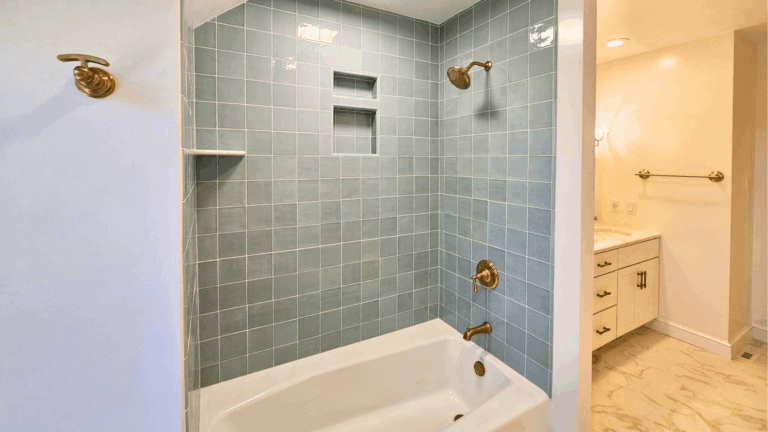 Modern bathroom remodel with gray tile shower, white soaking tub, and brass fixtures in Pottstown