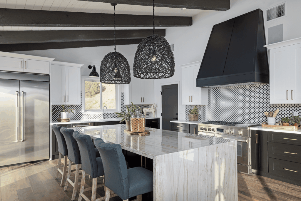 Modern kitchen remodel with white cabinetry, black and white tile backsplash, marble island, and black pendant lights