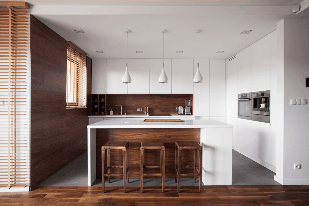 Modern kitchen remodel with white cabinetry, dark wood backsplash, island countertop, and pendant lighting