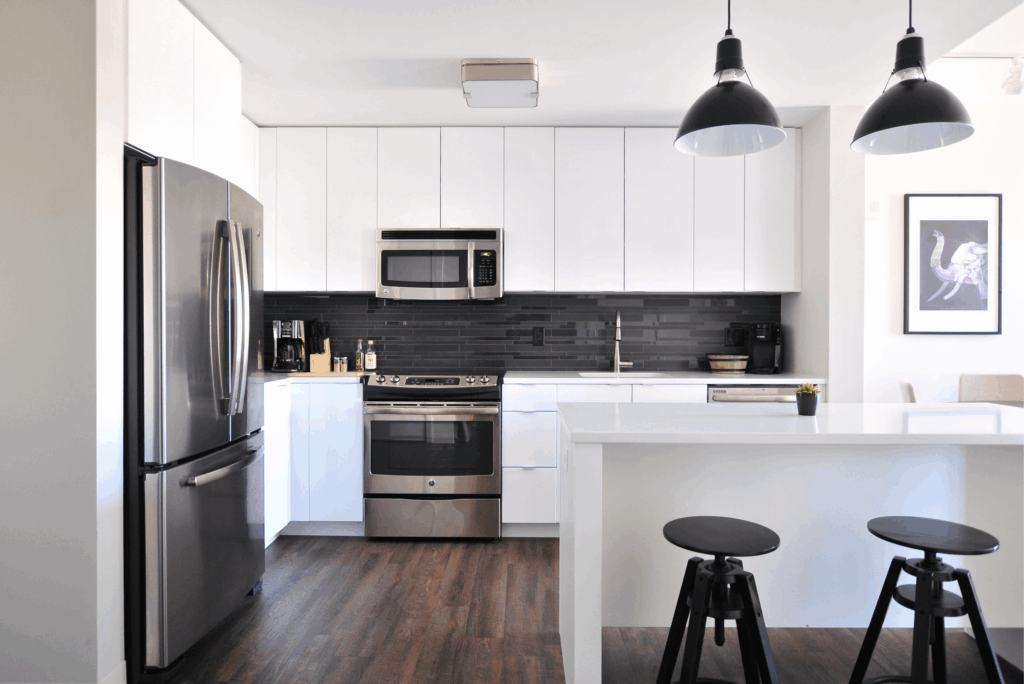 Modern kitchen remodel with white shaker cabinets, black subway tile backsplash, stainless steel appliances, and white quartz island countertops