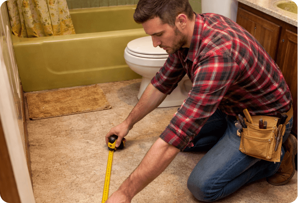 Contractor measuring bathroom floor with tape measure during home renovation project