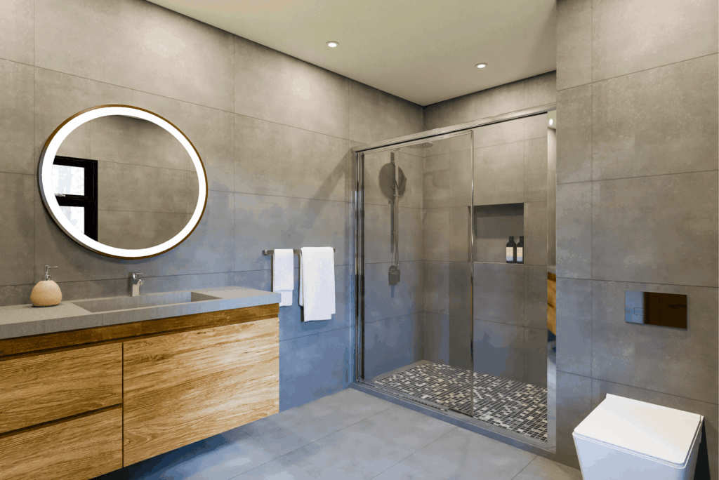 Modern bathroom remodel with walk-in shower, floating wood vanity, and illuminated round mirror