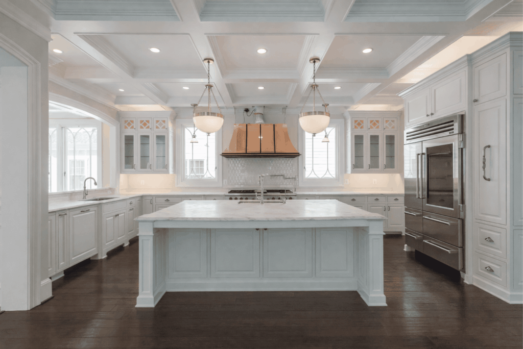 Luxury white kitchen remodel with coffered ceiling, island, stainless steel appliances, and hardwood flooring by Pottstown Construction