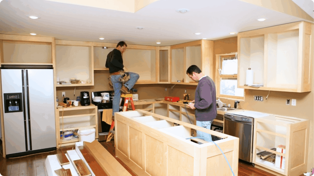 Our Construction Process 4 Kitchen remodeling in progress with contractors installing custom wood cabinets and stone countertops