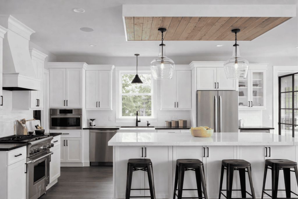 Modern white kitchen remodel with stainless steel appliances, quartz island countertop, and black bar stools