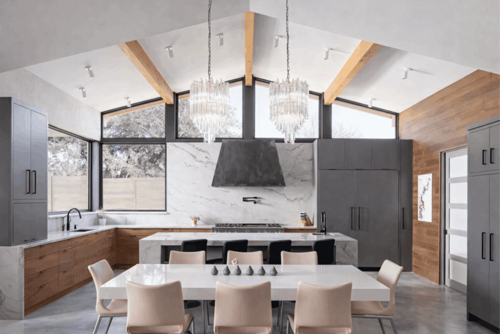 Modern kitchen and dining room remodel with marble countertops, wood cabinets, and vaulted ceiling with skylights