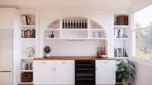 Custom white built-in cabinetry with arched shelving, wood countertop, and wine cooler in modern home remodel