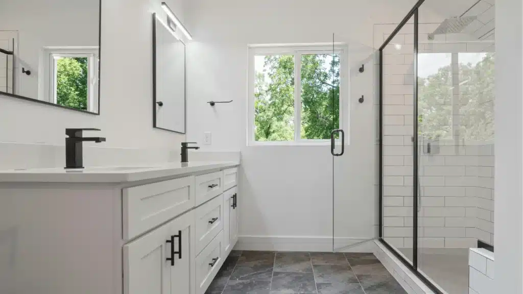 Modern master bathroom with white shaker vanity, black fixtures, subway tile shower, and frameless glass enclosure