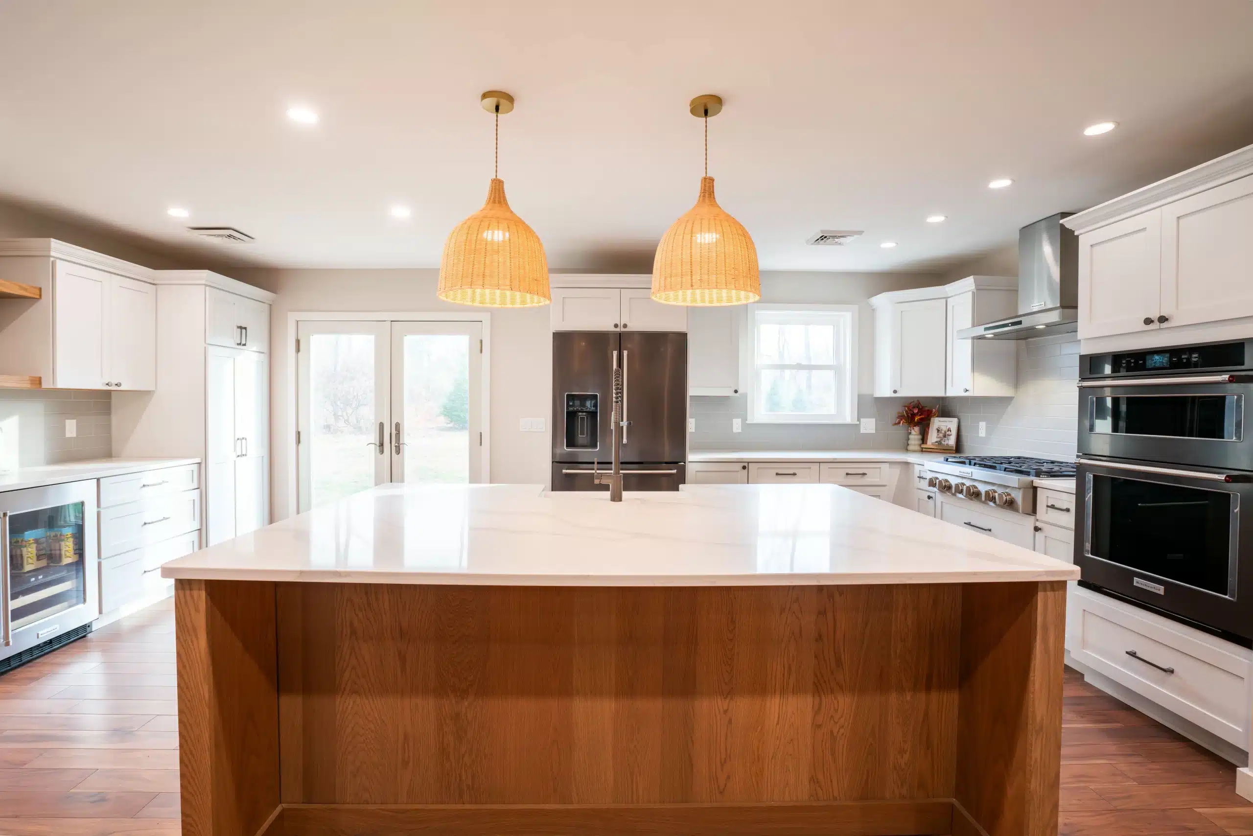 Modern kitchen remodel with white shaker cabinets, wood island, quartz countertops, and stainless steel appliances