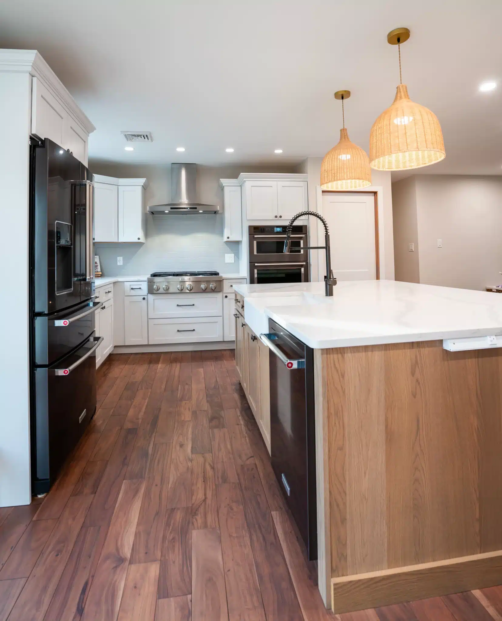 Modern kitchen remodel with white shaker cabinets, quartz countertops, wood island, black appliances, and pendant lighting