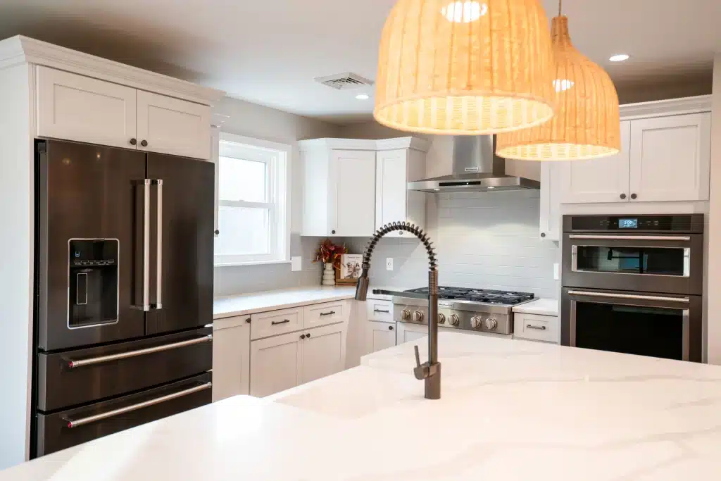 Modern kitchen remodel with white shaker cabinets, black stainless appliances, quartz countertop, and pendant lighting