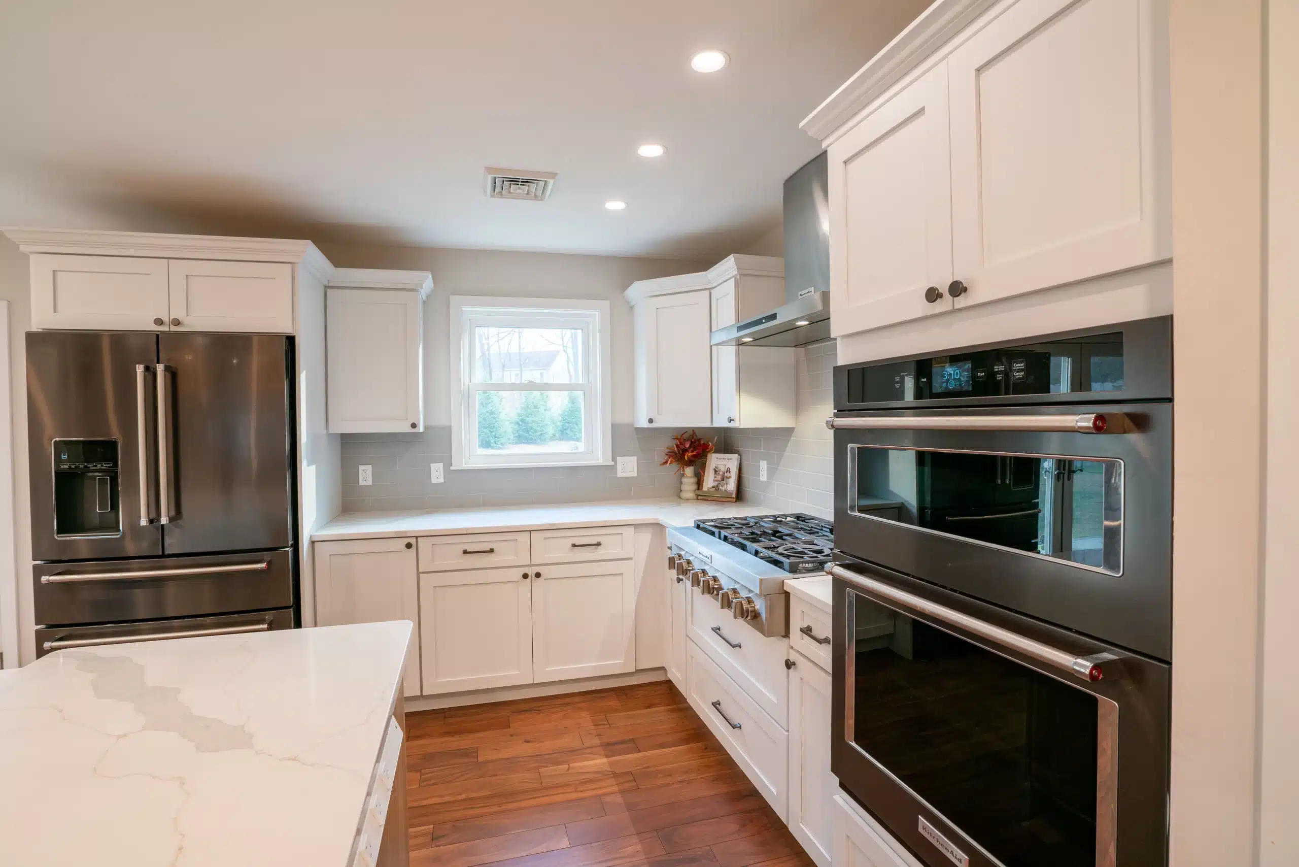 Modern kitchen remodel with white shaker cabinets, stainless steel appliances, and quartz countertops by Pottstown Construction