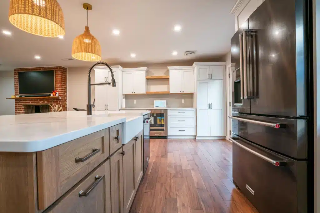 Modern kitchen remodel with white shaker cabinets, quartz countertops, stainless steel appliances, and hardwood flooring