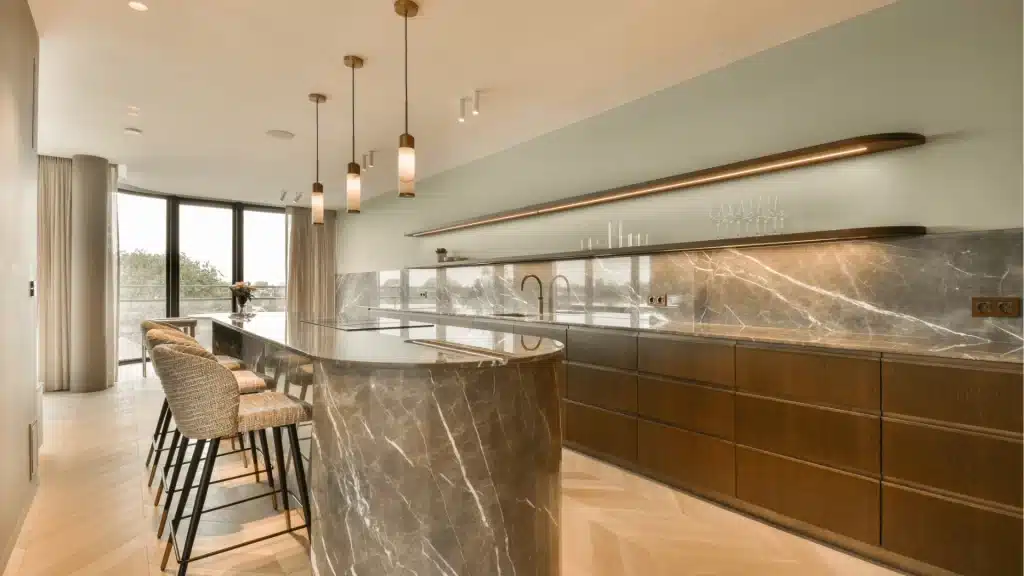 Modern luxury kitchen with marble island, wood cabinetry, pendant lighting, and panoramic windows
