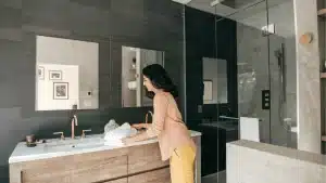 Modern bathroom remodel with dark tile, floating wood vanity, marble countertop, and frameless glass shower enclosure