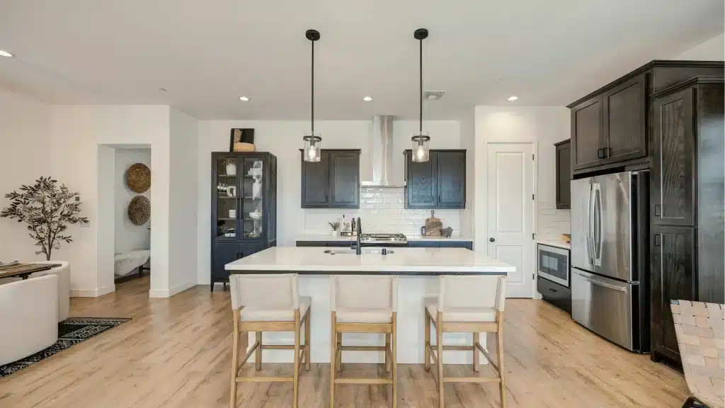 Modern kitchen remodel with white island, dark cabinetry, stainless steel appliances, and wood flooring