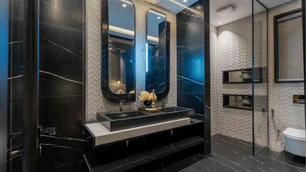 Modern luxury bathroom with black marble tile walls, floating vanity sink, herringbone backsplash, and frameless glass shower enclosure