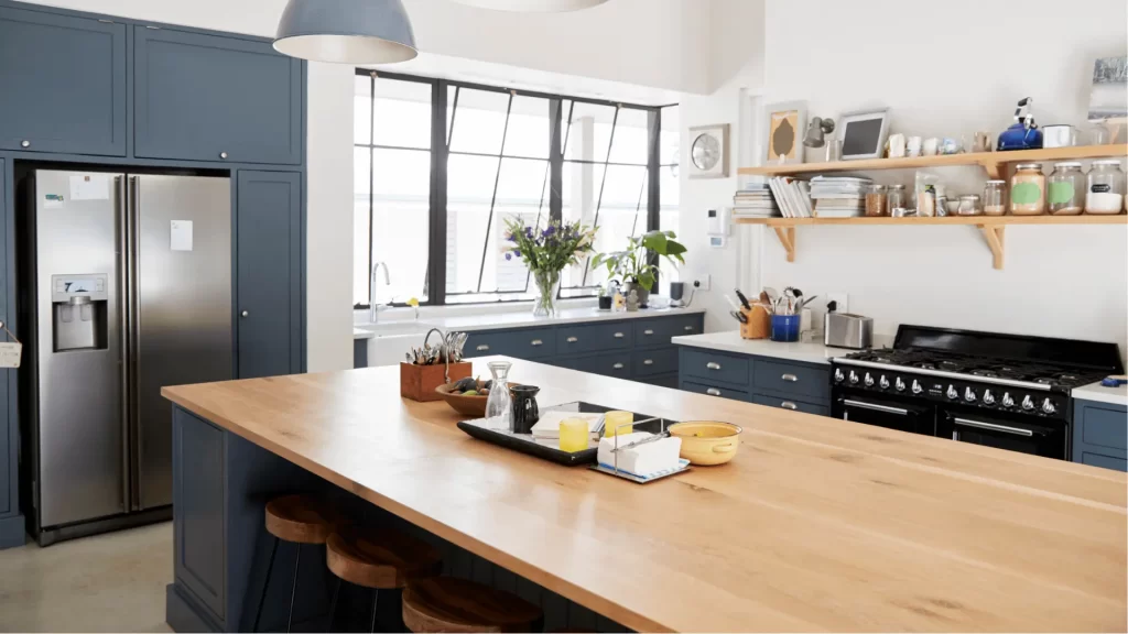 Modern kitchen remodel with navy blue shaker cabinets, wood countertops, stainless steel appliances, and open shelving