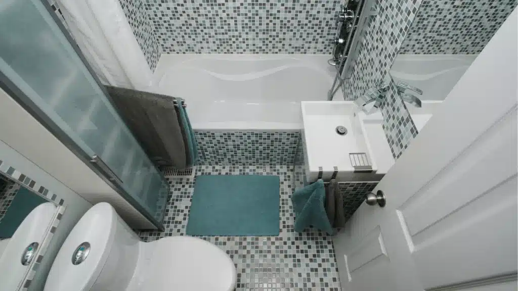 Modern bathroom remodel with mosaic tile shower, white vanity, and dual toilets