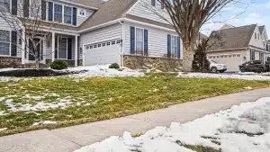 Modern white vinyl siding home with two-car garage and stone accents in suburban neighborhood