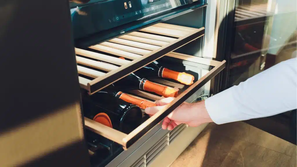 Built-in wine cooler drawer with temperature control displaying bottles inside stainless steel kitchen appliance