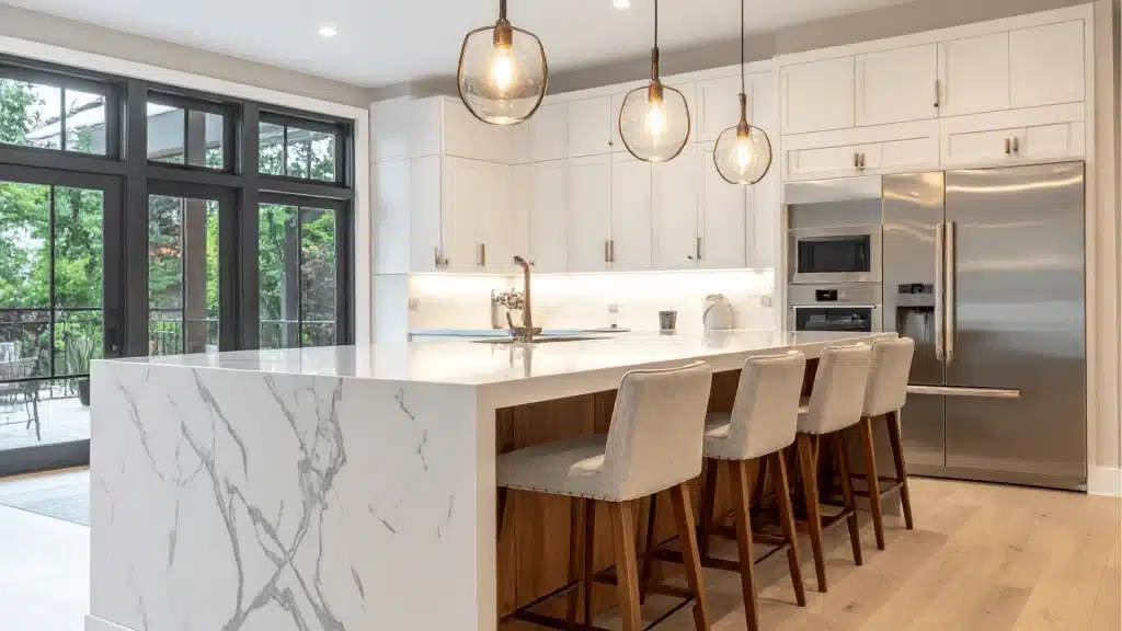 Modern luxury kitchen remodel with white cabinetry, marble island, stainless steel appliances, and pendant lighting