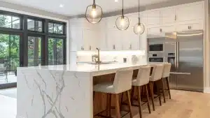 Modern luxury kitchen remodel with white cabinetry, marble island, stainless steel appliances, and pendant lighting