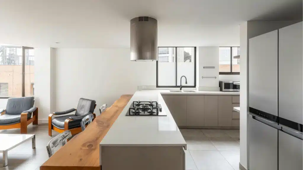 Modern kitchen remodel with gray cabinets, white quartz island, stainless steel range hood, and gas cooktop
