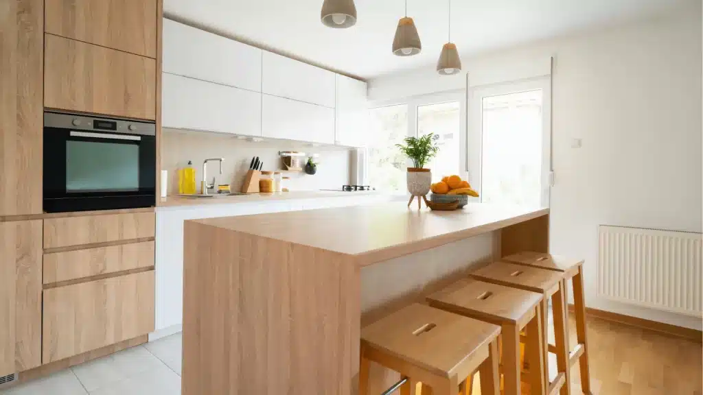 Modern kitchen remodel with white and natural wood cabinets, island countertop, and pendant lighting