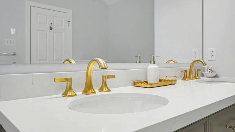 Modern bathroom vanity with white quartz countertop, brass faucets, and framed mirror by Pottstown Construction Company