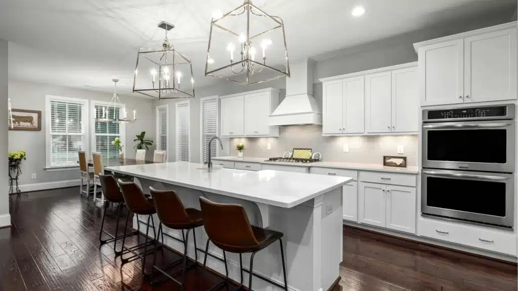 Modern kitchen remodel with white shaker cabinets, quartz countertop island, stainless steel appliances, and pendant lighting