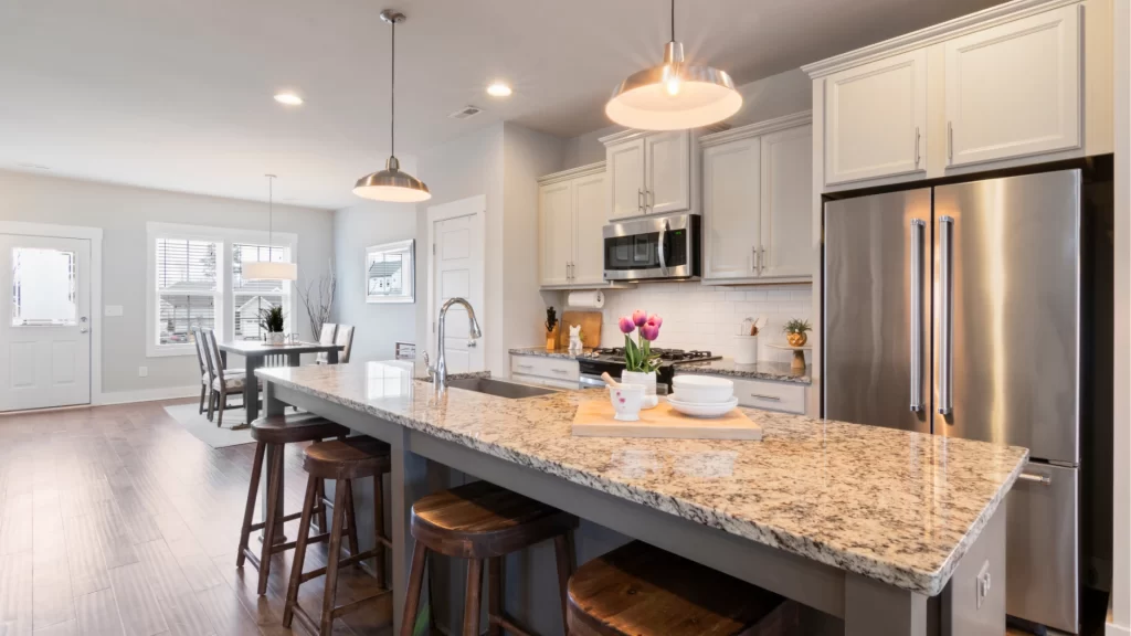 Modern kitchen remodel with white cabinetry, granite countertops, stainless steel appliances, and pendant lighting