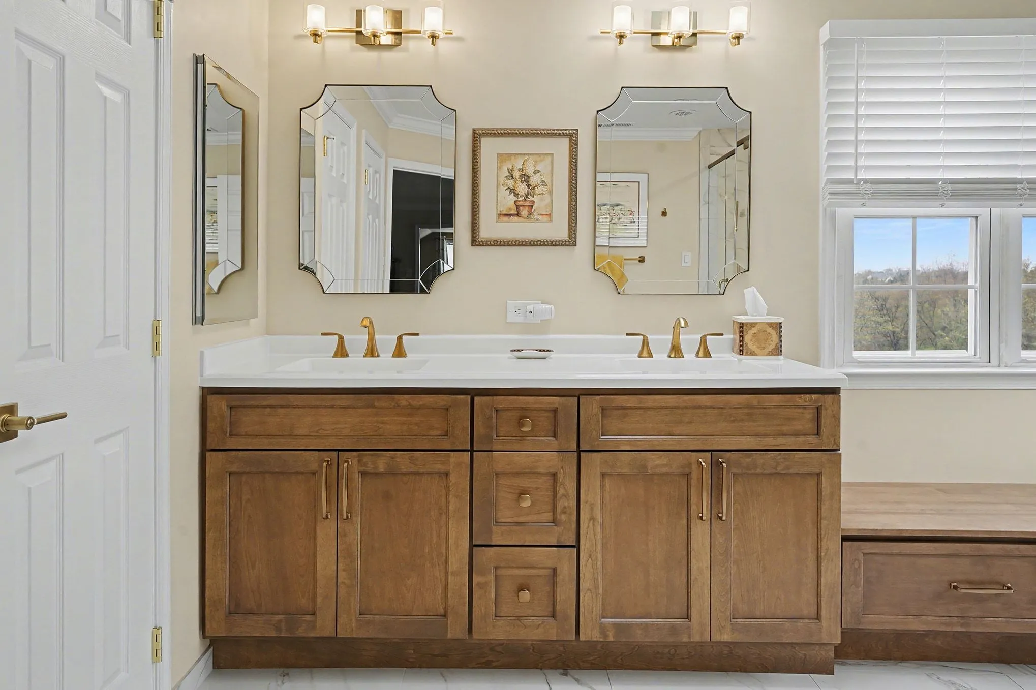Master bathroom with double vanity, honey-wood cabinetry, white quartz countertop, ornate framed mirrors, and large scenic windows.