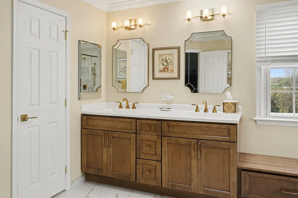 Master bathroom with double vanity, honey-wood cabinetry, three ornate framed mirrors, large windows with scenic views, and marble flooring.