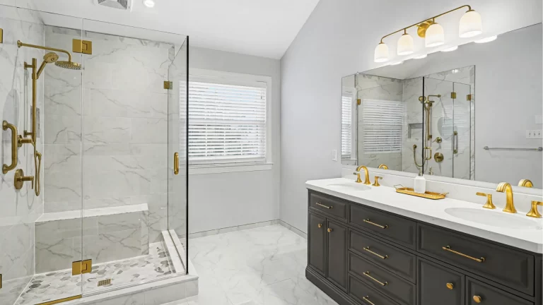 Modern luxury bathroom remodel with marble tile shower enclosure, dual vanity, and brass fixtures by Pottstown Construction Company