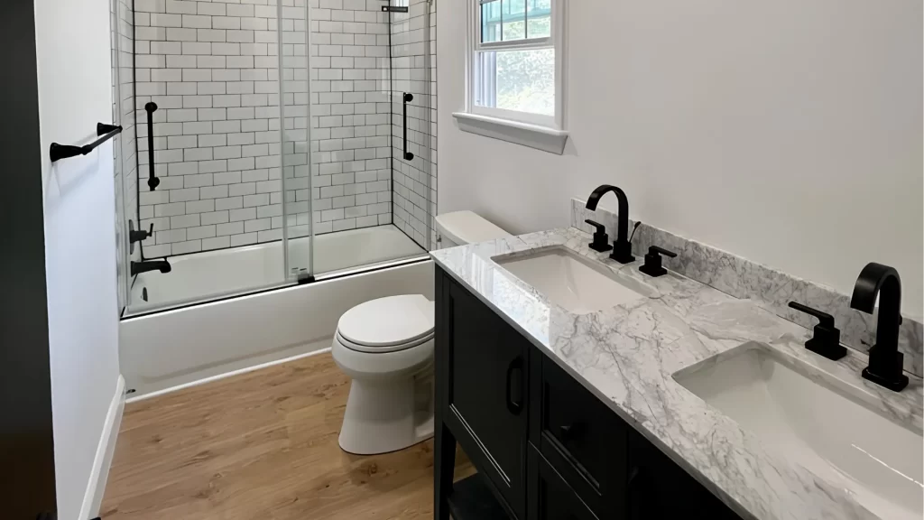 Modern bathroom remodel with marble countertops, black fixtures, subway tile shower, and dual vanity sink