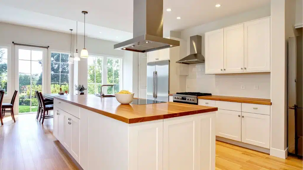 Spacious kitchen with butcher block countertop with white cabinets