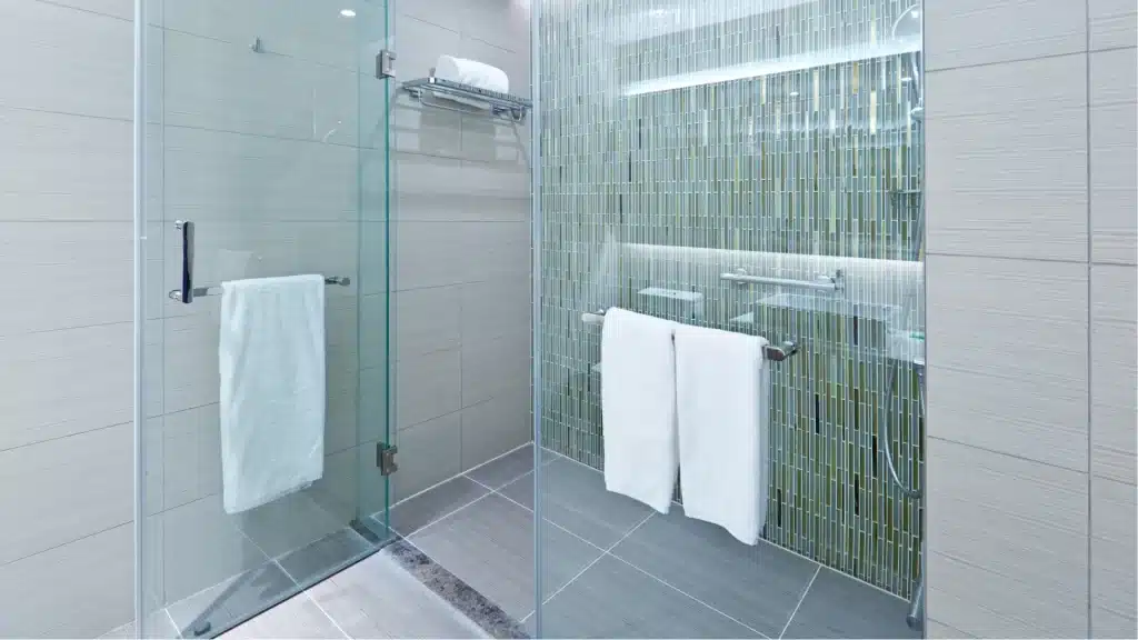 Modern bathroom shower renovation with frameless glass enclosure, gray tile floor, and white subway tile walls