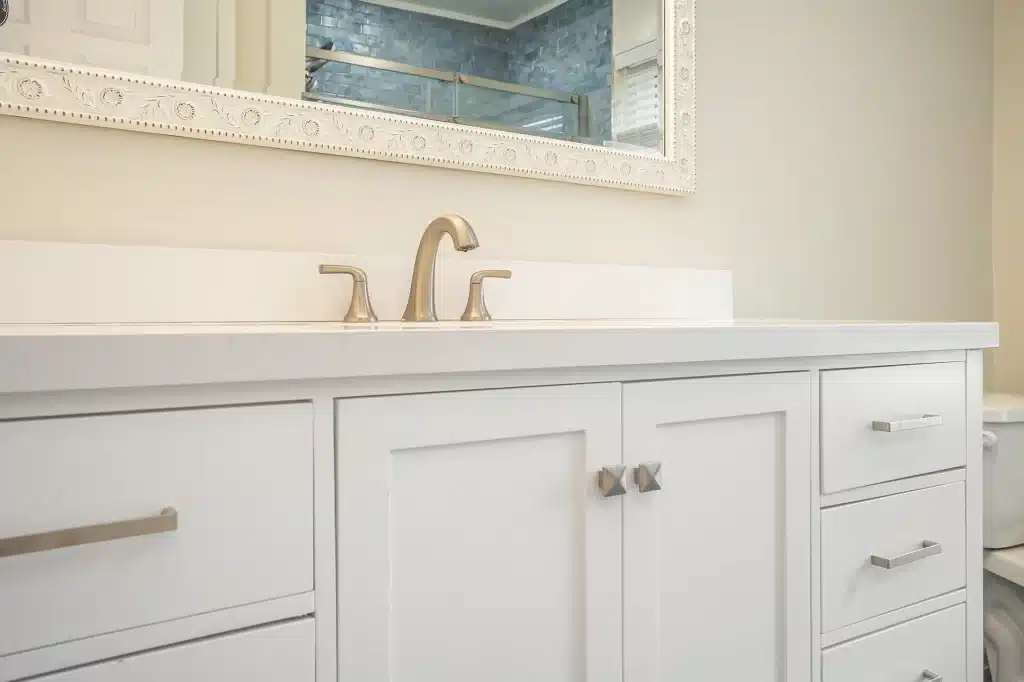 White shaker vanity with quartz countertop, nickel faucet, and framed mirror