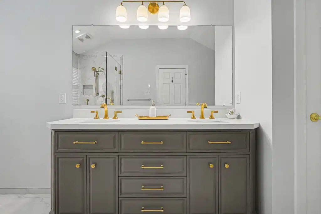 Front view of gray double vanity with gold hardware and wide wall mirror