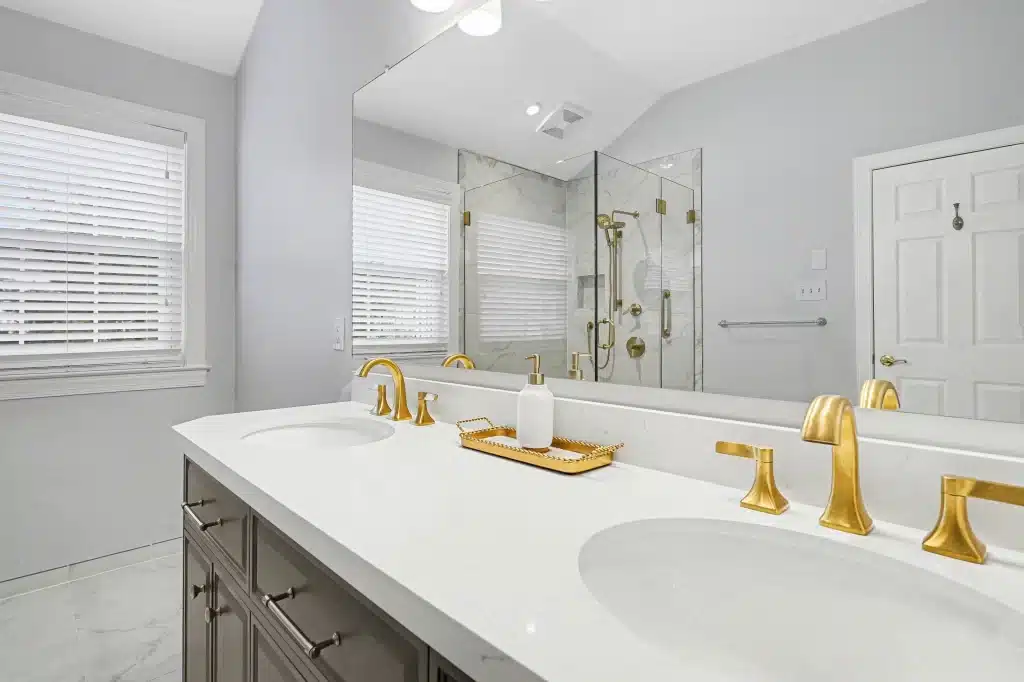 Double vanity closeup with gold faucets, white countertop, and large mirror
