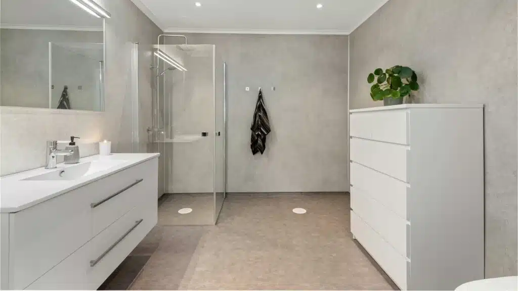 Modern bathroom remodel with white vanity, glass shower enclosure, and concrete flooring
