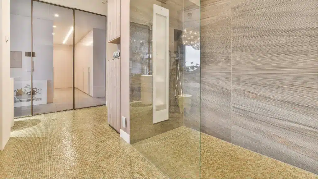 Modern bathroom remodel with frameless glass shower enclosure, mosaic tile flooring, and textured tile walls